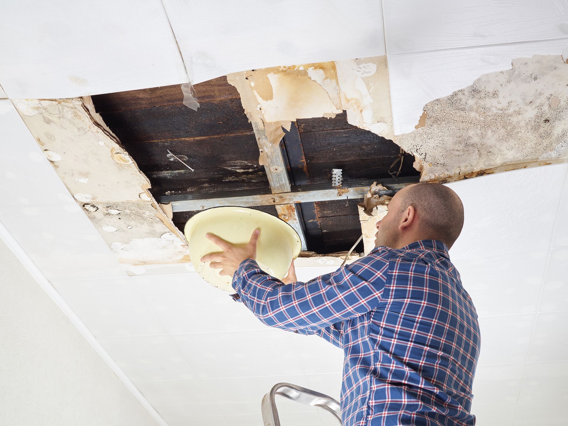 Asbestos Abatement — Hathaway Environmental in Solon, OH A man is looking through a hole in the ceiling while holding a plate.